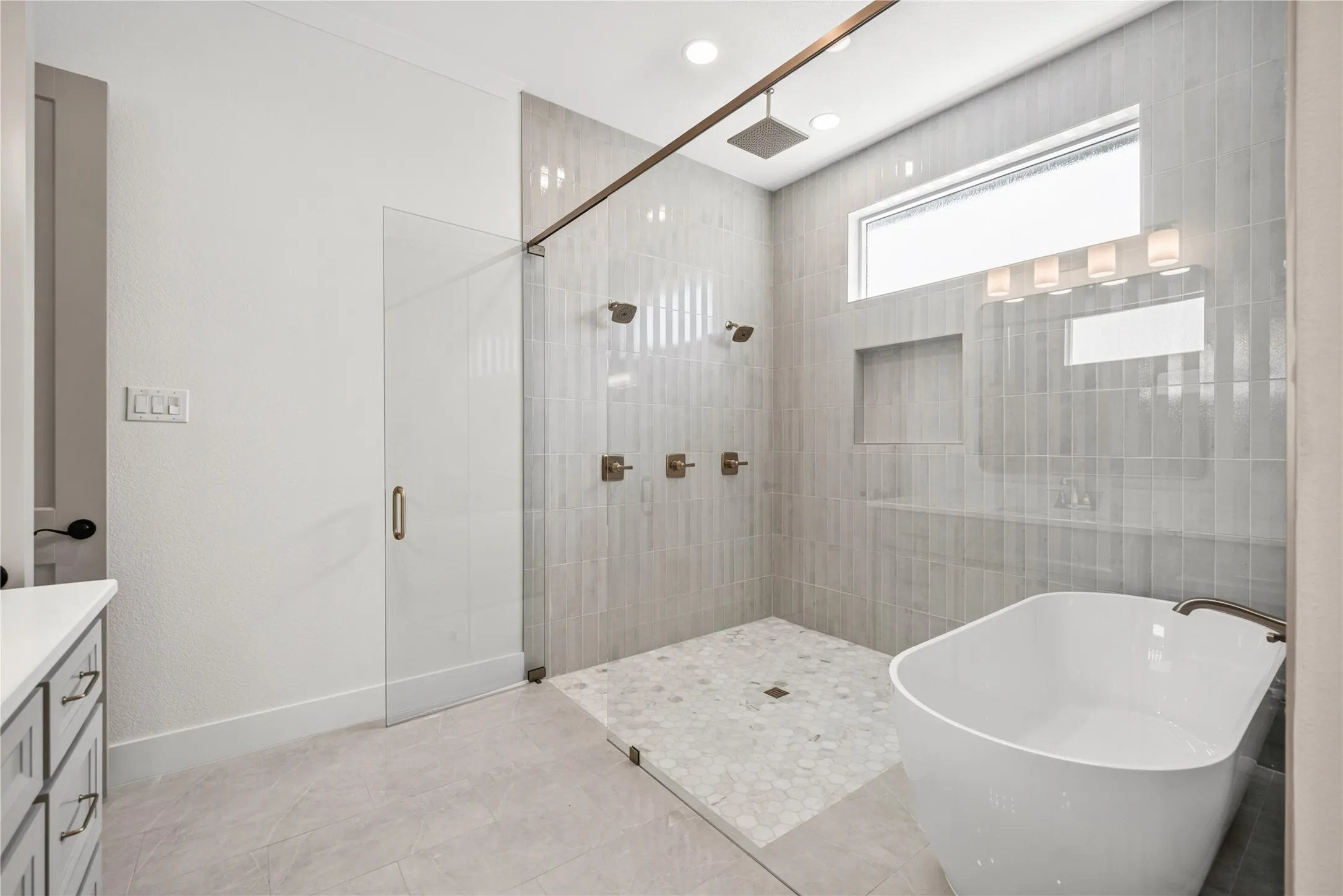 Spacious bathroom featuring a frameless glass shower enclosure with vertical tile, a rain showerhead, and multiple wall-mounted shower fixtures