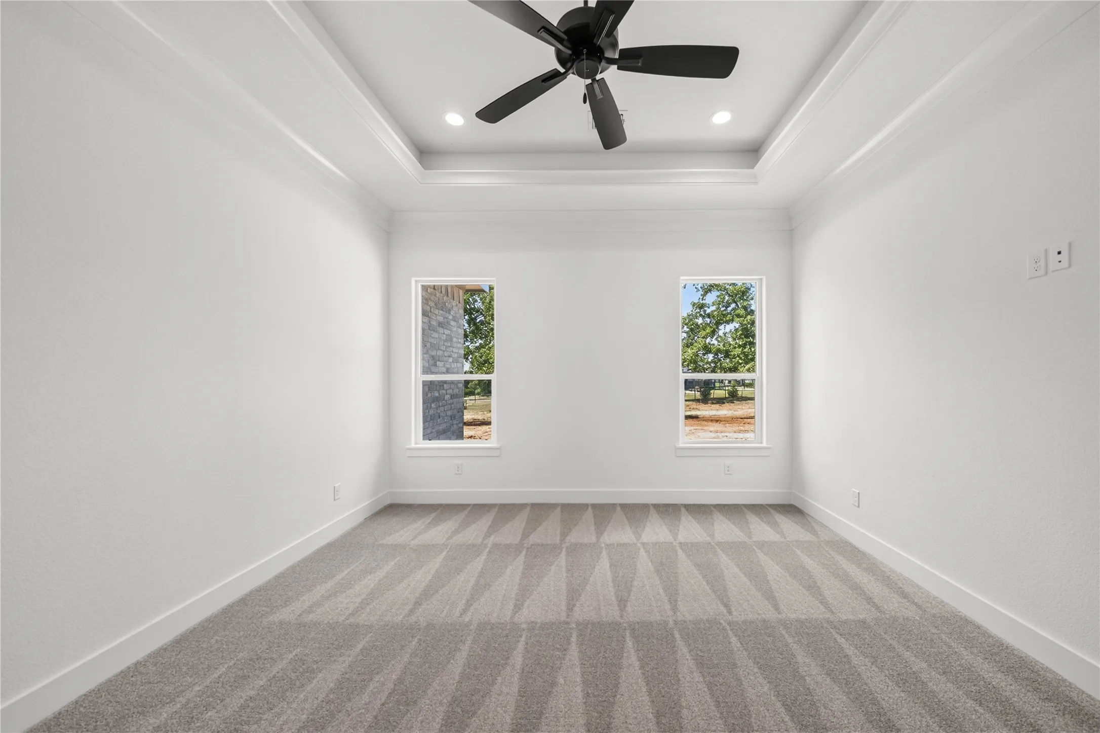 White-painted interior room featuring a tray ceiling with recessed lighting and a ceiling fan