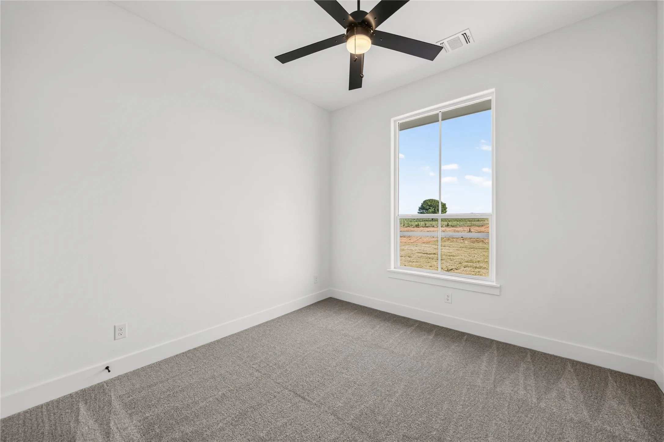 Carpeted room featuring a large window, neutral wall tones, a ceiling fan, and white trim