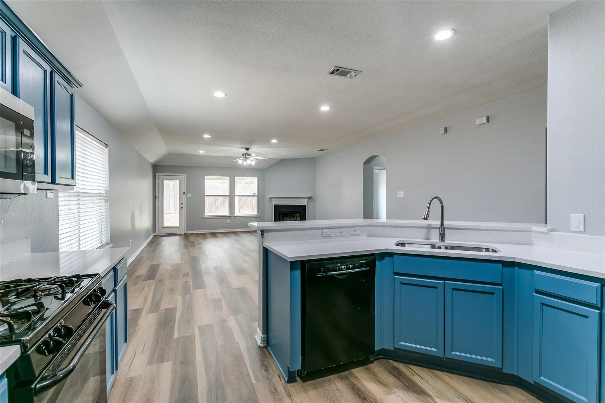 Kitchen featuring blue cabinetry, a stainless steel sink with a gooseneck faucet, white countertops, and integrated appliances