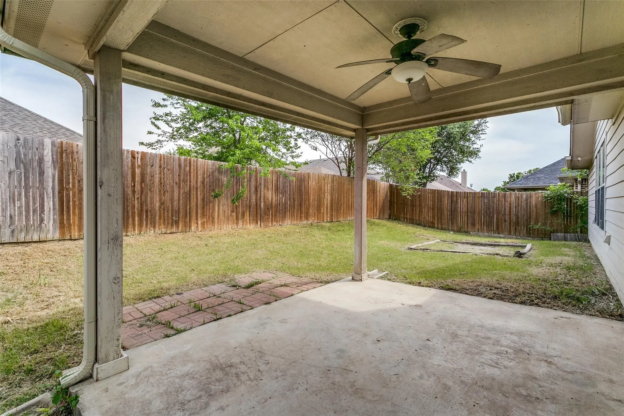 Covered concrete patio with an integrated ceiling fan and recessed lighting