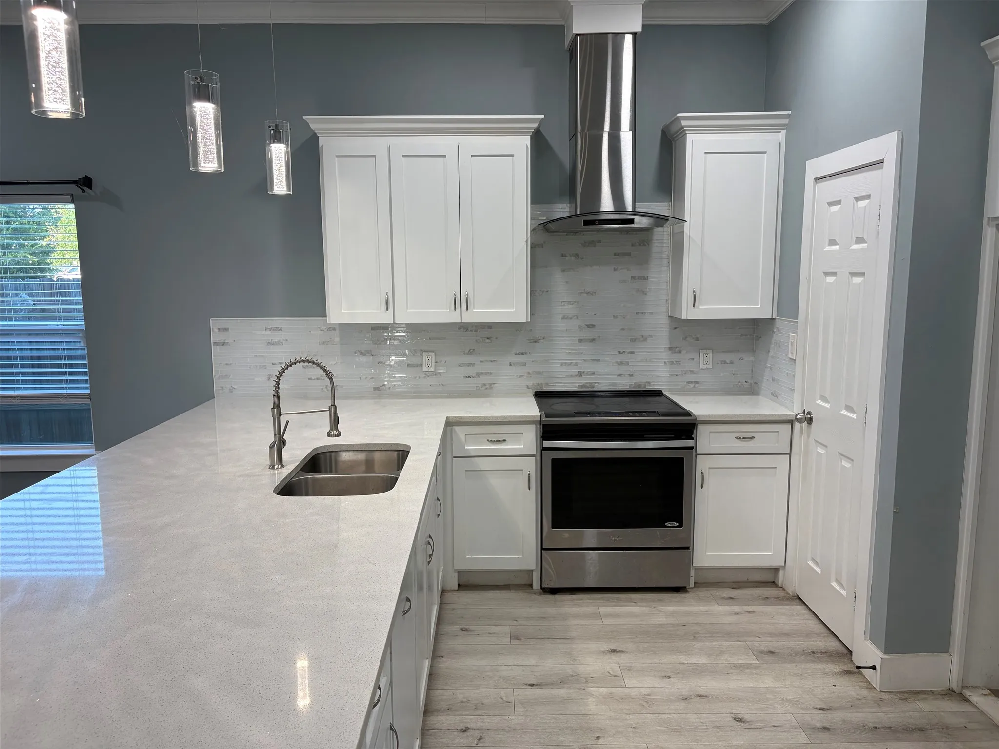 Kitchen featuring white shaker cabinetry, light-toned countertops, a full stainless steel appliance suite, and a tile backsplash
