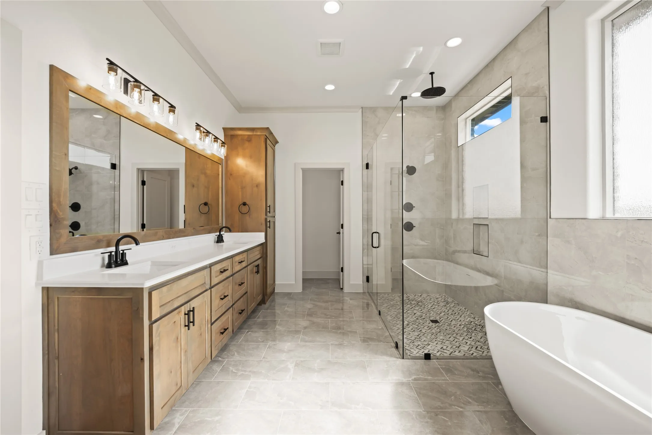 Spacious bathroom featuring a double vanity with wood cabinetry, white countertops, and black fixtures
