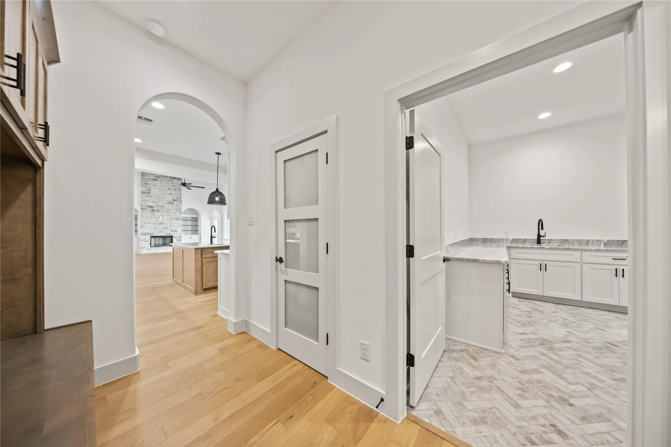 Light wood-finish flooring extending from the hallway into an open-concept living area with an arched entry