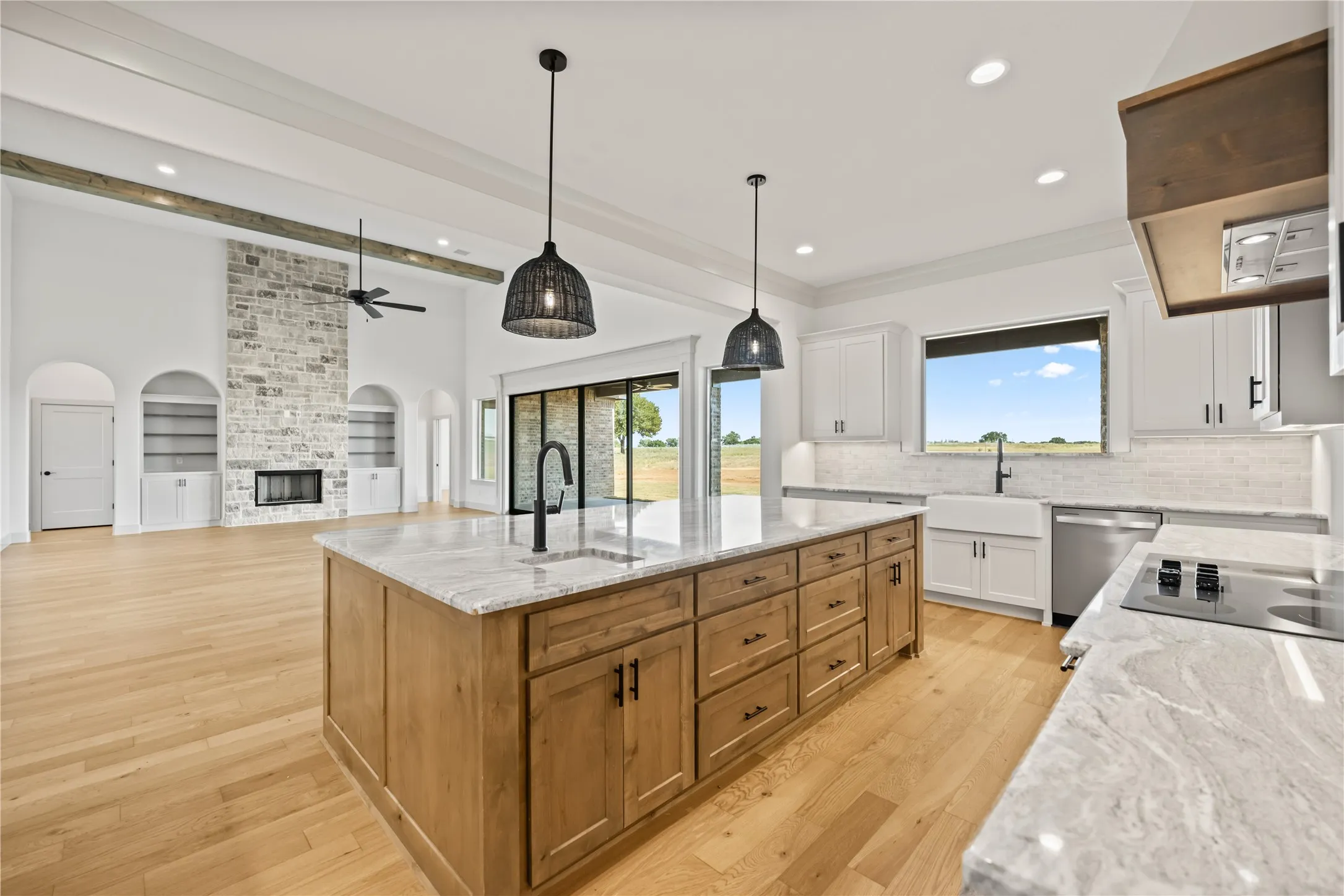 Kitchen island with light wood cabinetry, stone countertop, and matte black fixtures