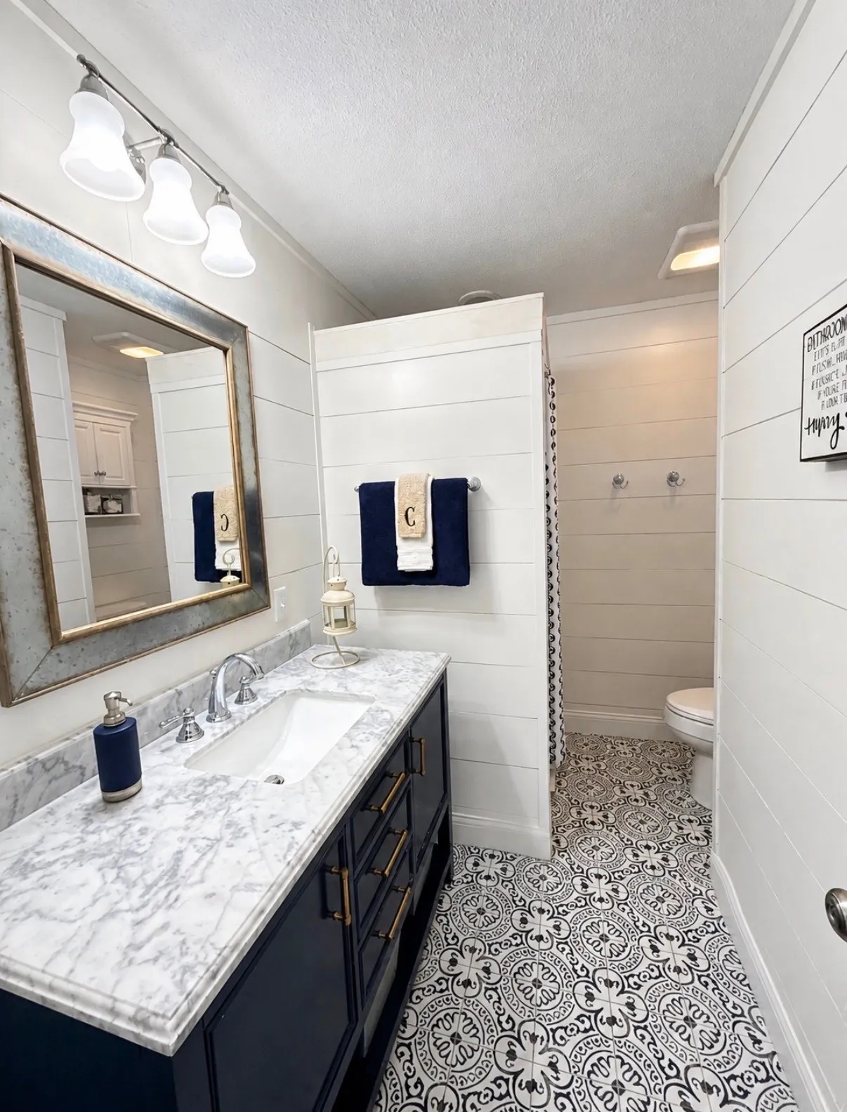 Hall bath has granite topped vanity, gorgeous tiled floor, wooden walls, and shower.