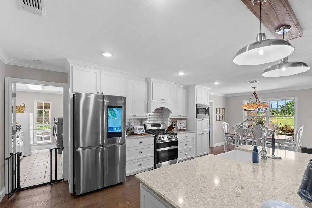 Fully modern and expansive kitchen.  Huge island with breakfast bar with farmhouse style sink and pendant lighting. 5-burner gas range and full suite of stainless appliances. Subway tile backsplash, custom cabinets and granite countertops.