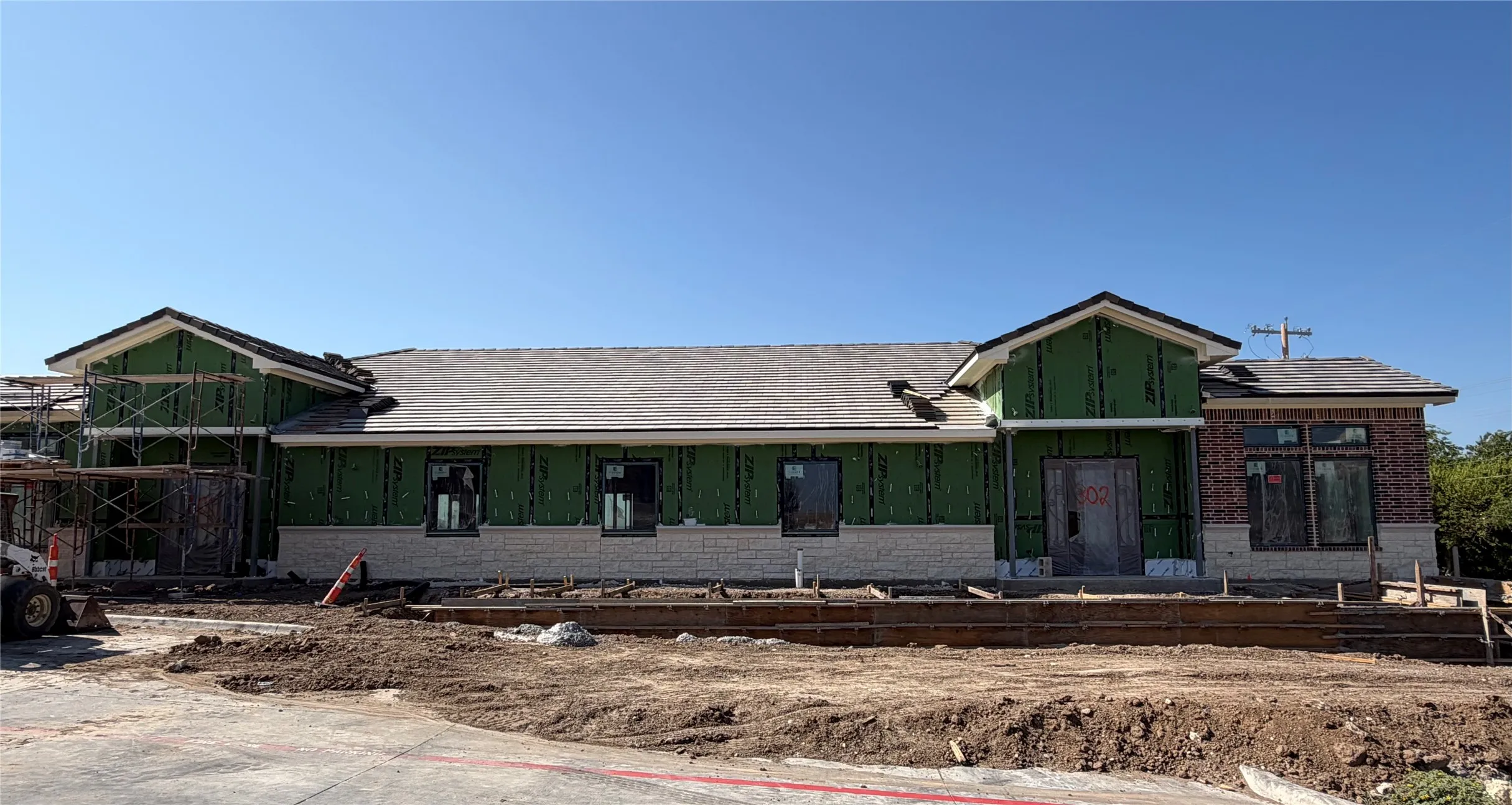 New construction property featuring brick and stone veneer, multiple window openings, and an asphalt shingle roof