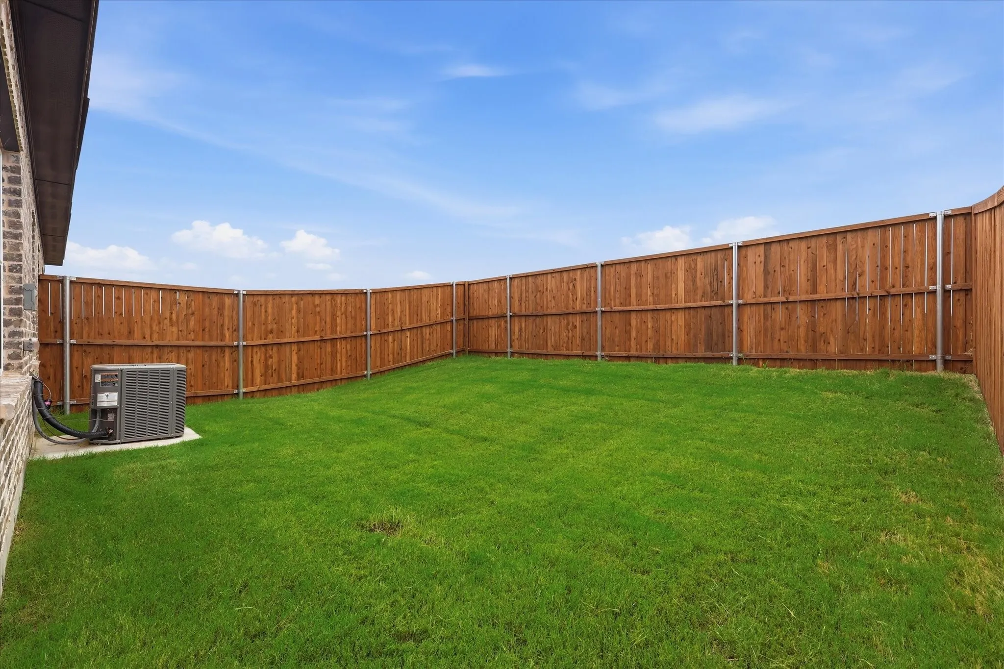 Expansive backyard featuring a manicured lawn and a privacy fence