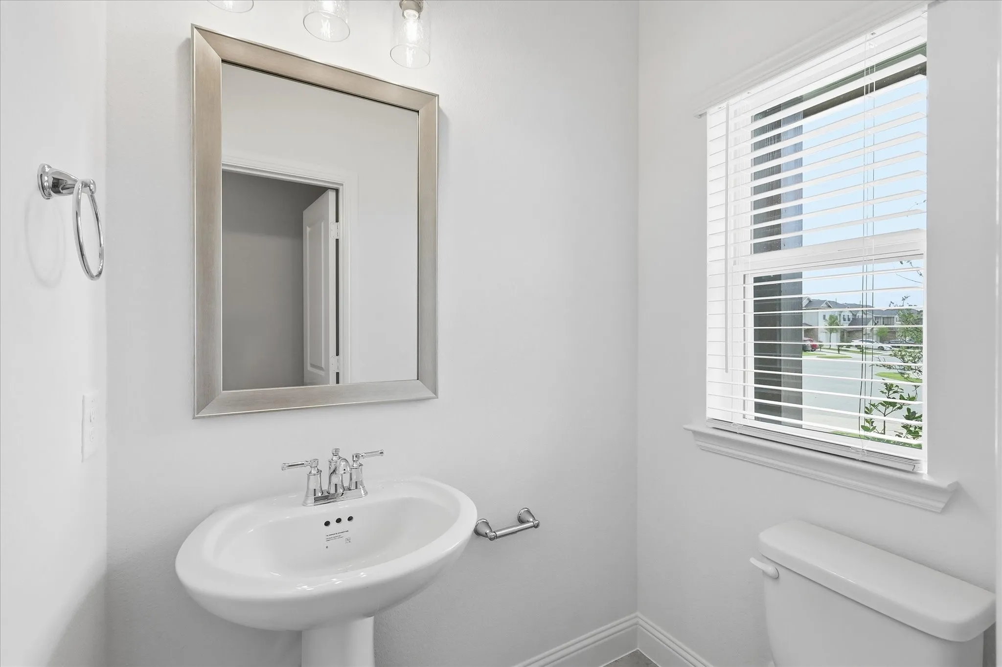 Pedestal sink with chrome fixtures and an overhead vanity light