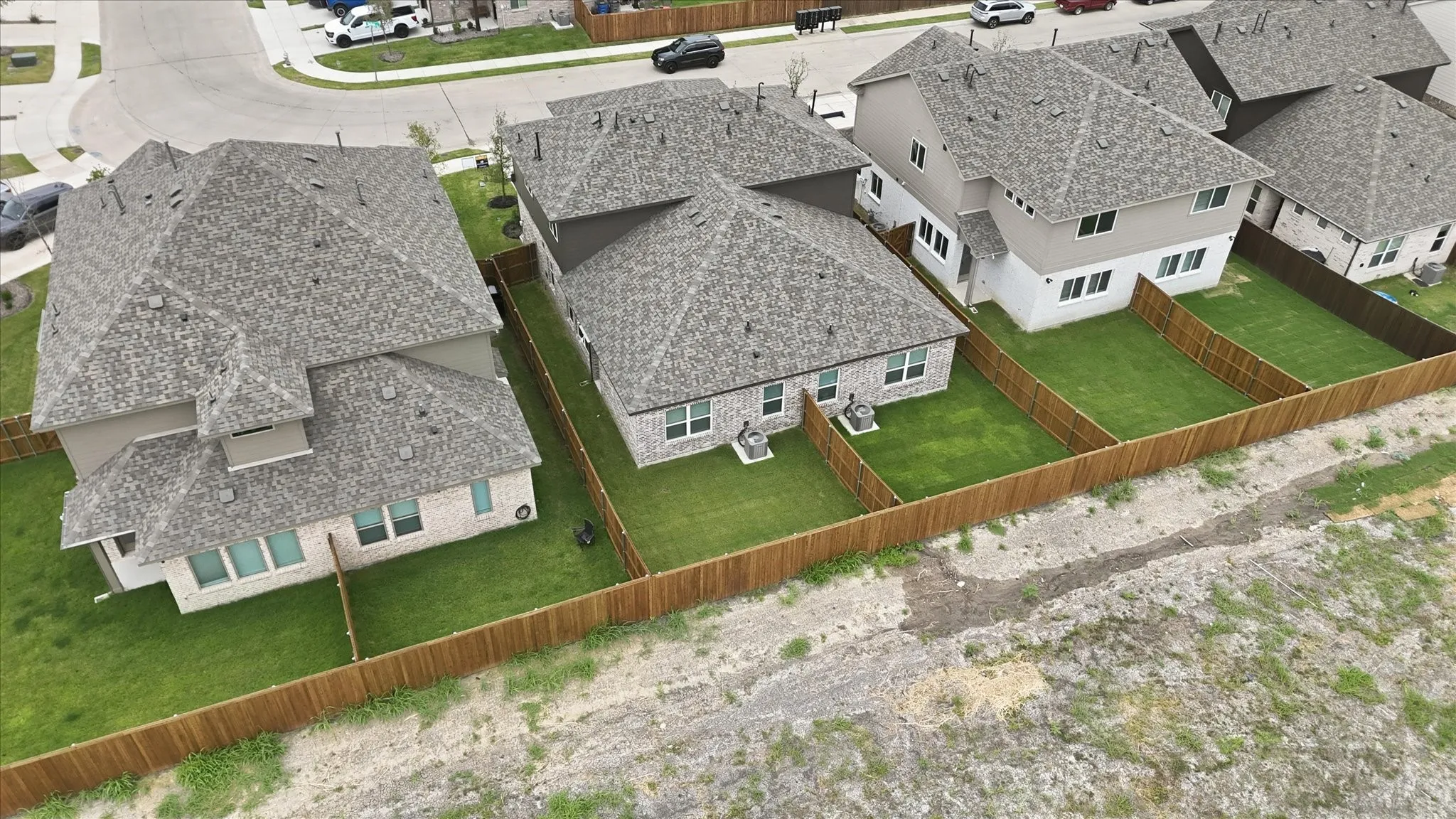 Newly constructed residences featuring shingle roofing, fenced backyards with manicured lawns, and exterior wall siding