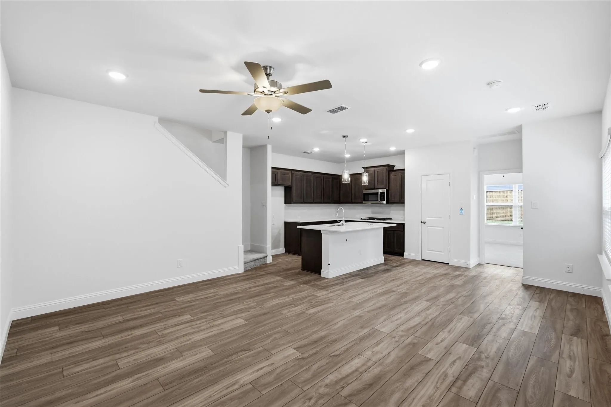 Open-concept living space featuring wood-finish flooring, recessed lighting, and a ceiling fan