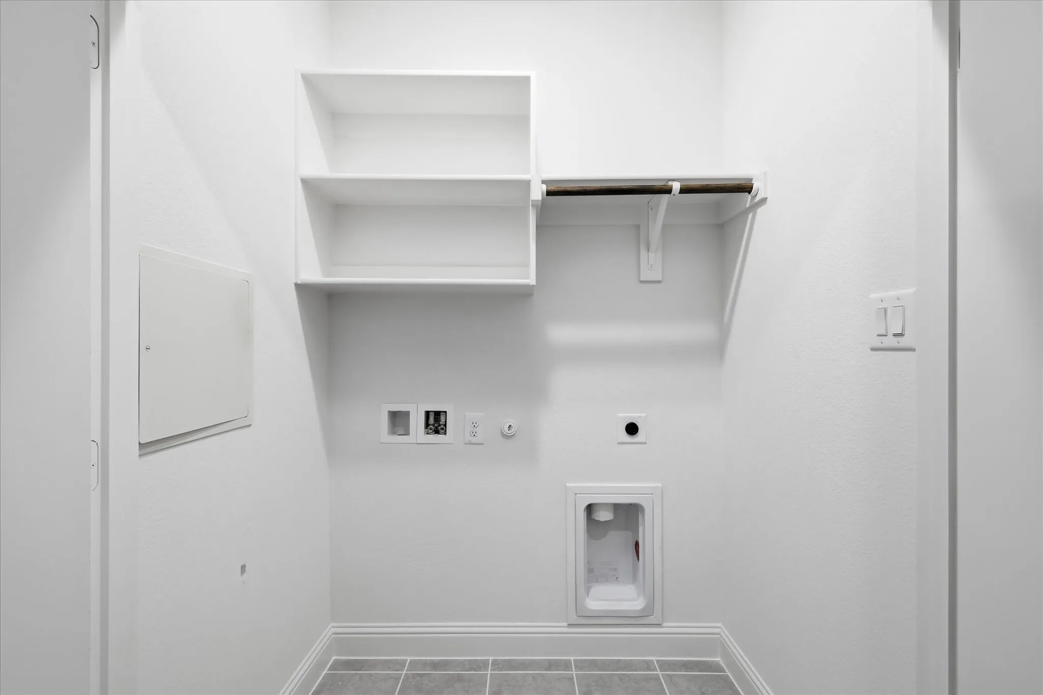 Dedicated laundry area featuring white shelving, a clothes rod, and gray tile flooring