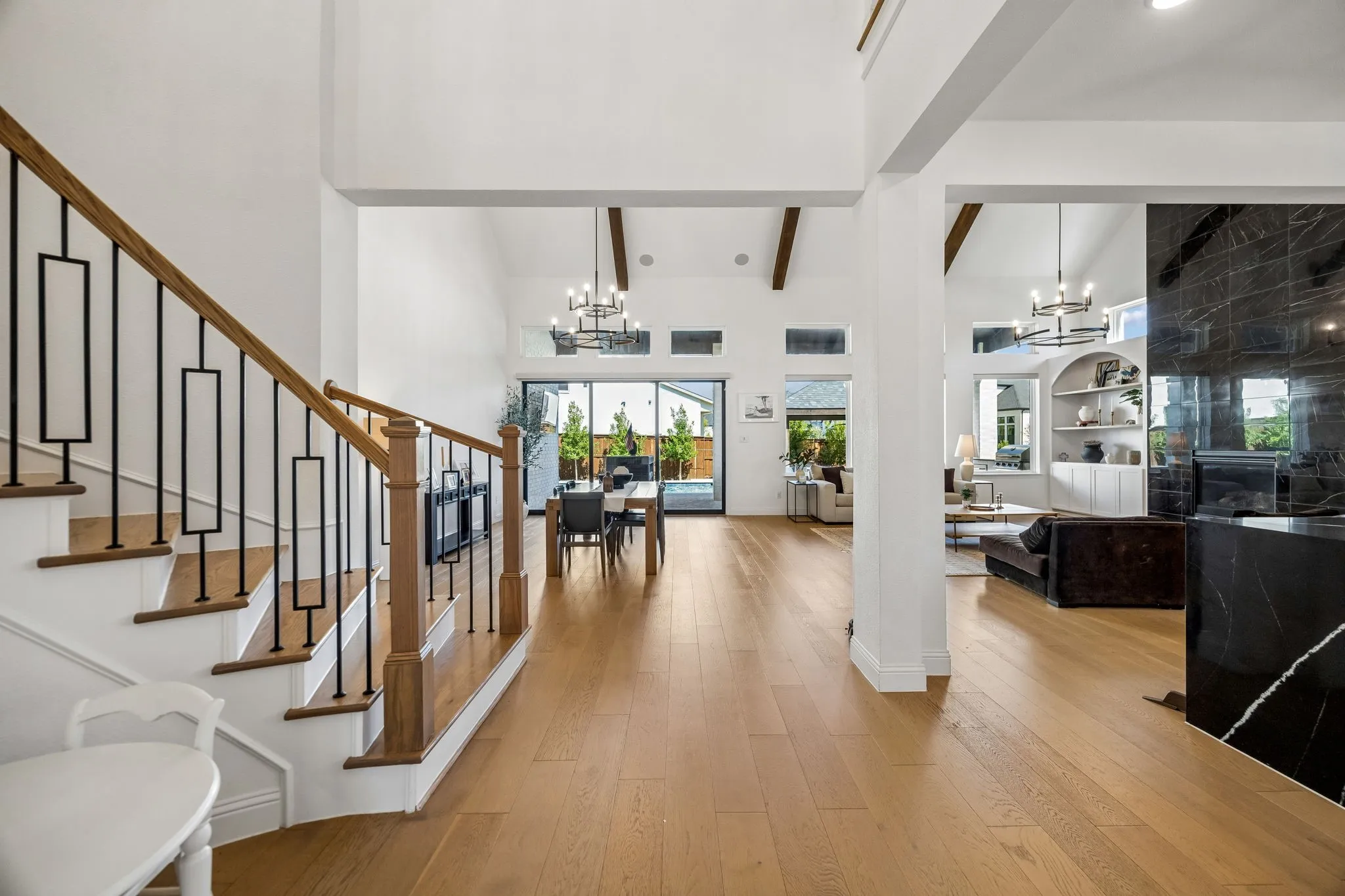 Grand entry foyer featuring wood-finish flooring, an open-tread staircase with decorative metal balusters, and a vaulted ceiling