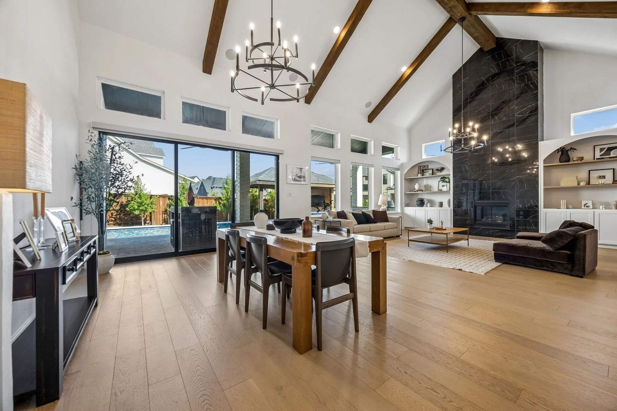 Kitchen features a waterfall island with black veined stone, white cabinetry, and stainless steel appliances, complemented by wood-finish flooring