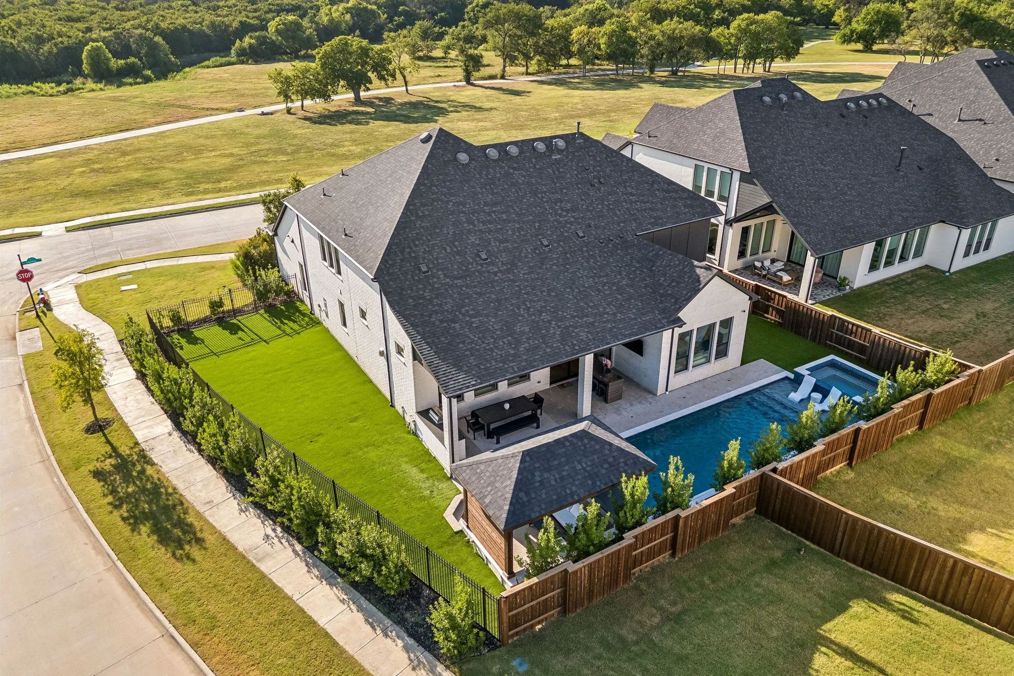 Rear exterior featuring a dark-tiled roof, private pool with integrated spa, covered patio, and wooden privacy fencing