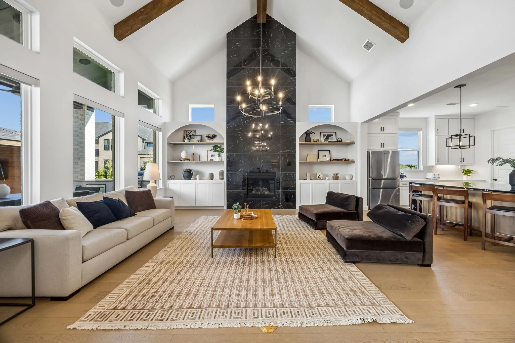 Vaulted ceiling with exposed wood beams, a floor-to-ceiling stone fireplace, and wood-finish flooring