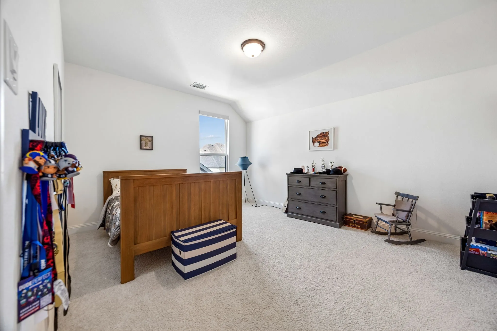 Expansive carpeted room featuring a sloped ceiling, bright white walls, a single window, and a flush mount ceiling light fixture