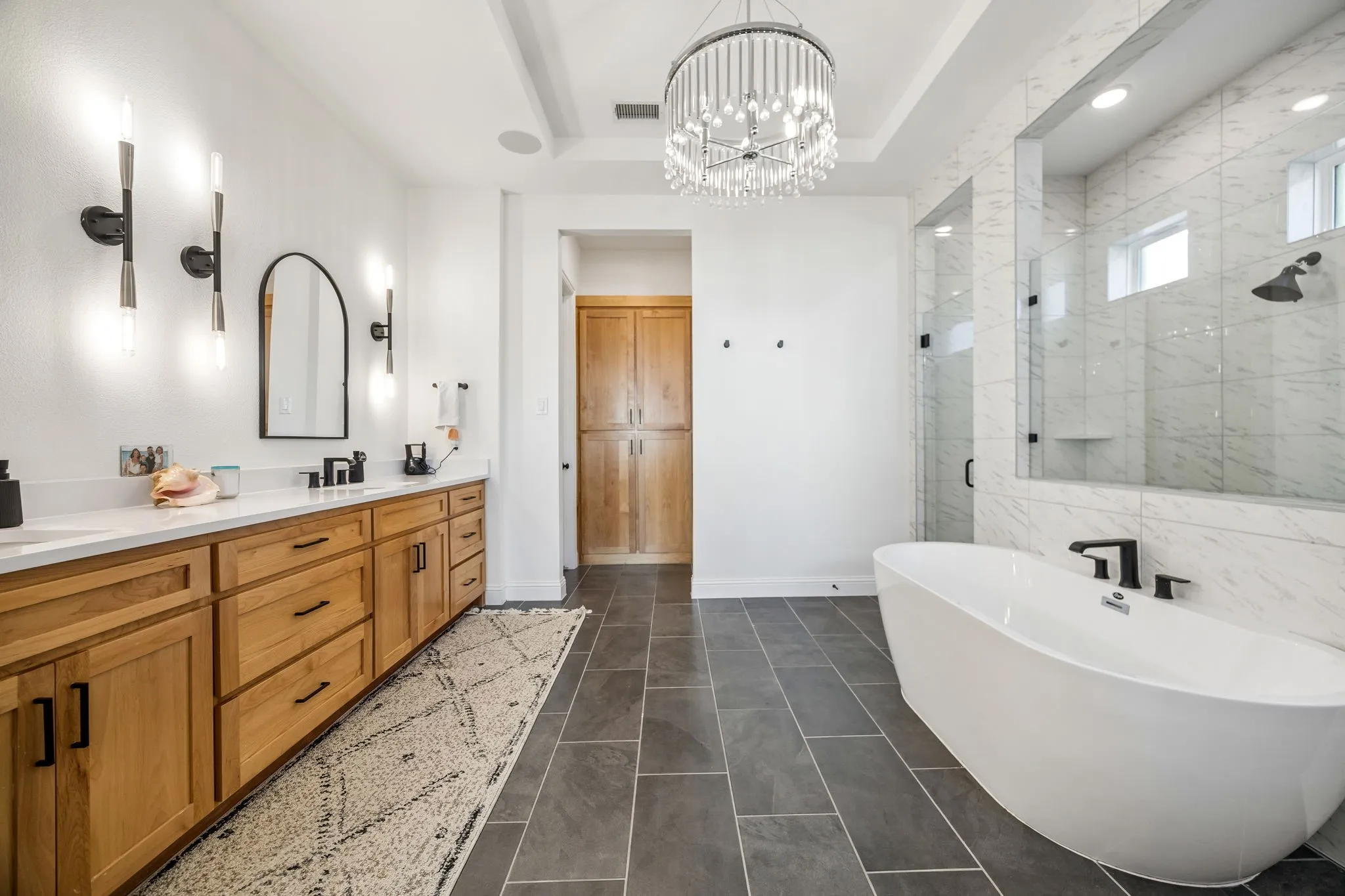 Spacious room featuring wood-finish flooring, a tiered ceiling, and a prominent chandelier
