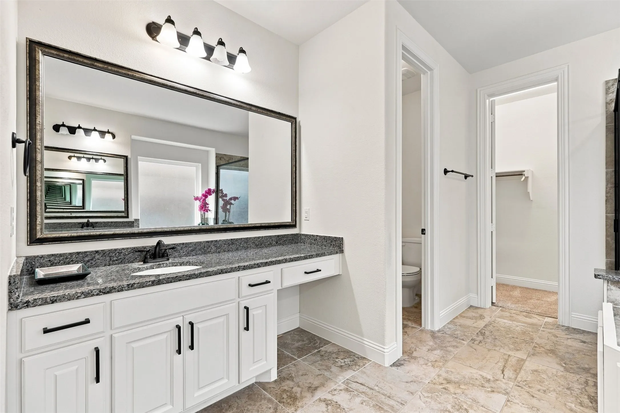 Contemporary bathroom vanity featuring a granite countertop, undermount sink, and matte black fixtures