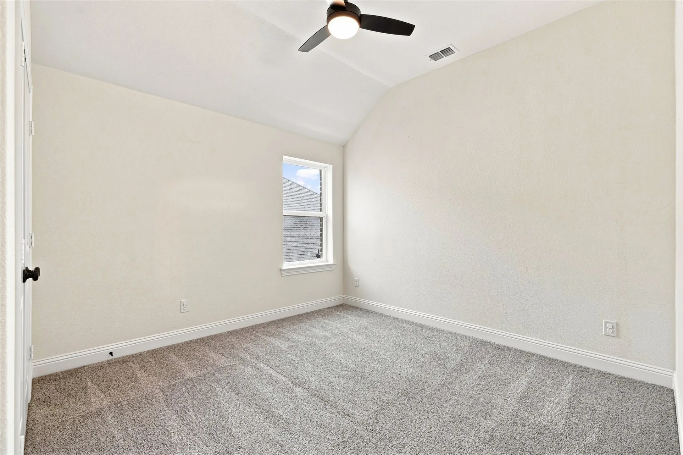 Bedroom featuring vaulted ceilings, neutral-toned carpeting, a window with exterior views, a ceiling fan with integrated lighting, and white baseboards