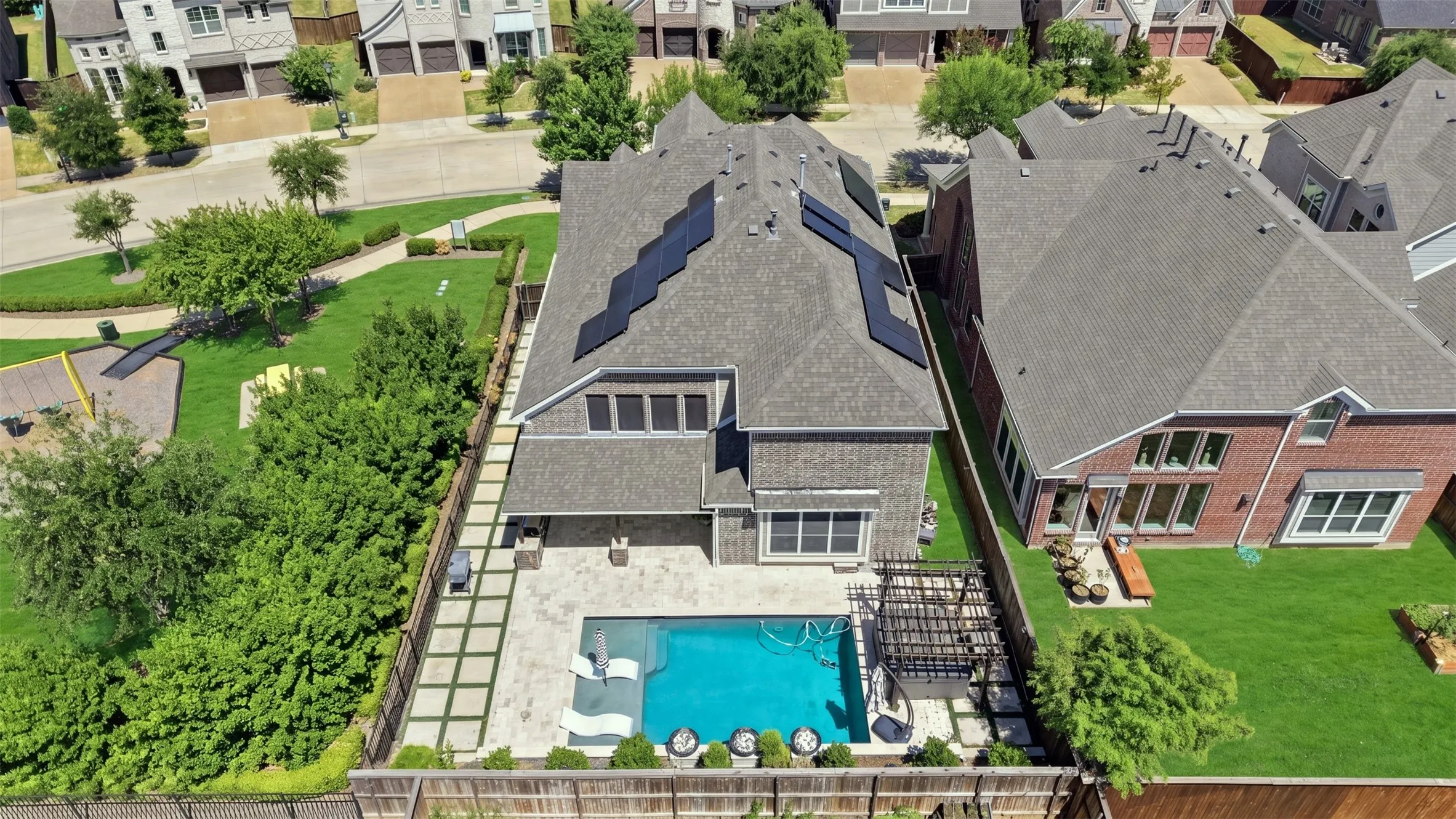 Rear exterior featuring a swimming pool, integrated patio with large format pavers, and a pergola