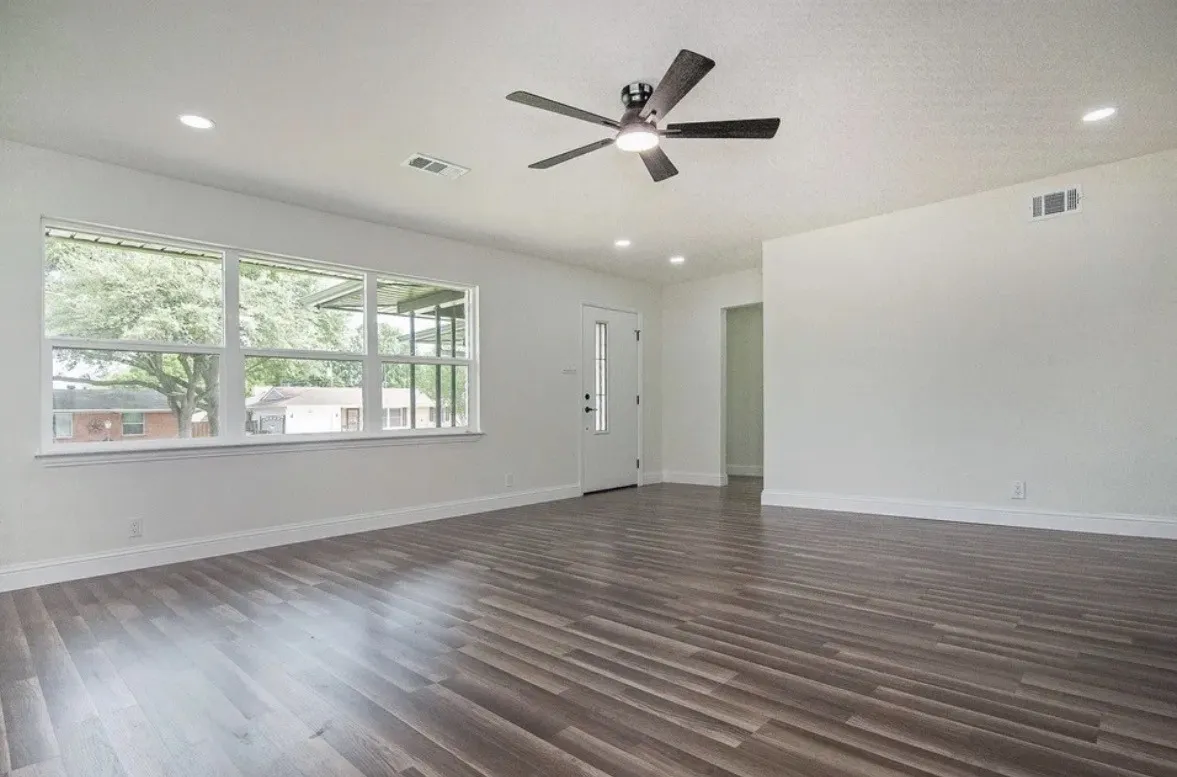 Spacious room featuring wood-finish flooring, a contemporary ceiling fan, recessed lighting, and a white entry door with glass inserts