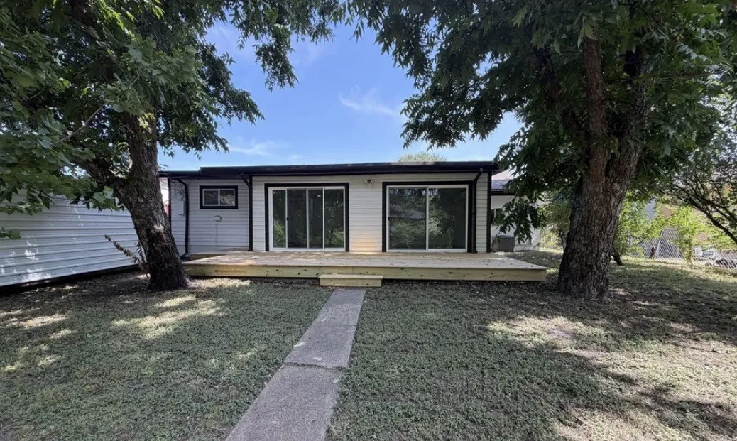 Rear exterior featuring a spacious wood deck with two sets of sliding glass doors