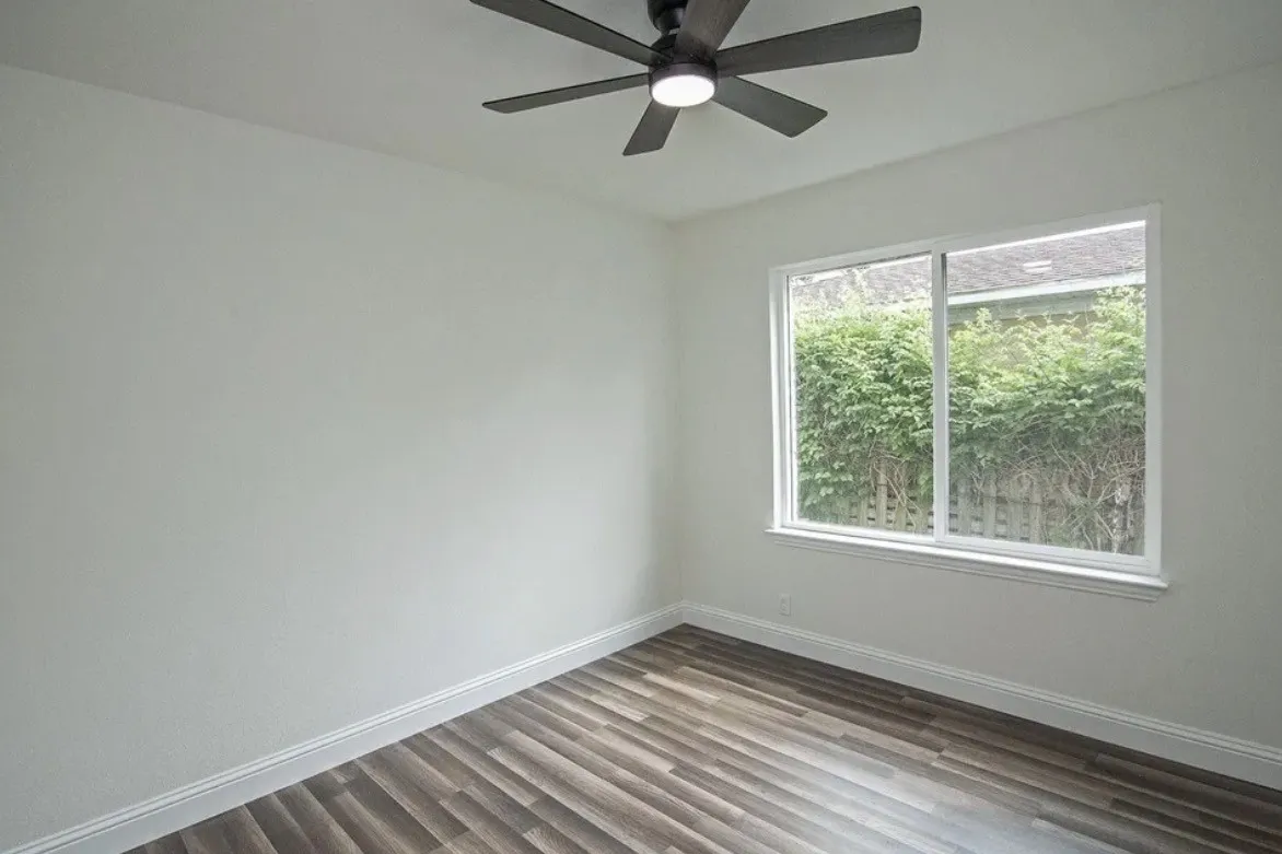 Room featuring wood-finish flooring, white baseboards, and light-toned walls