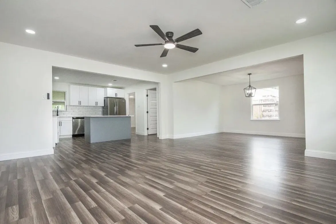 Spacious open-concept living area featuring wood-finish flooring, recessed lighting, and a contemporary ceiling fan