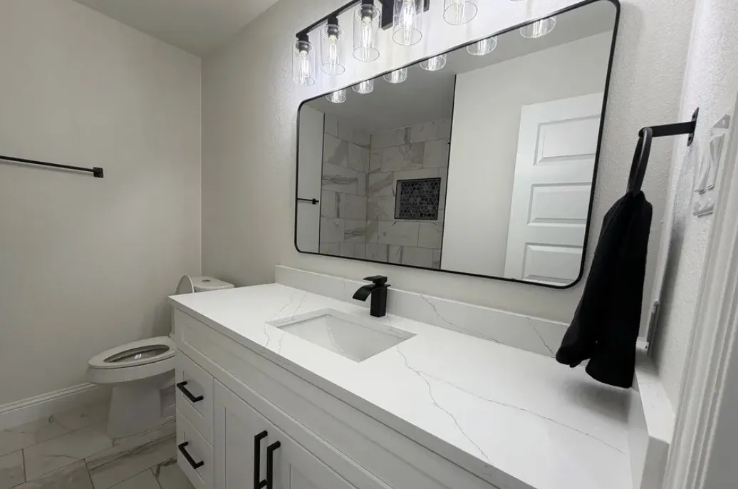 Modern vanity featuring a quartz countertop, integrated sink, matte black faucet, and coordinating hardware
