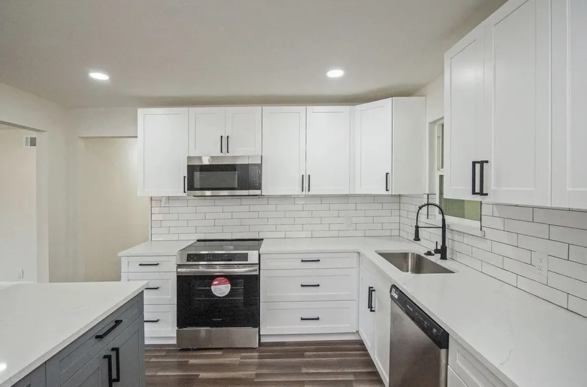 Kitchen featuring white shaker cabinetry, white subway tile backsplash, stainless steel appliances, white countertops, and dark wood-finish flooring