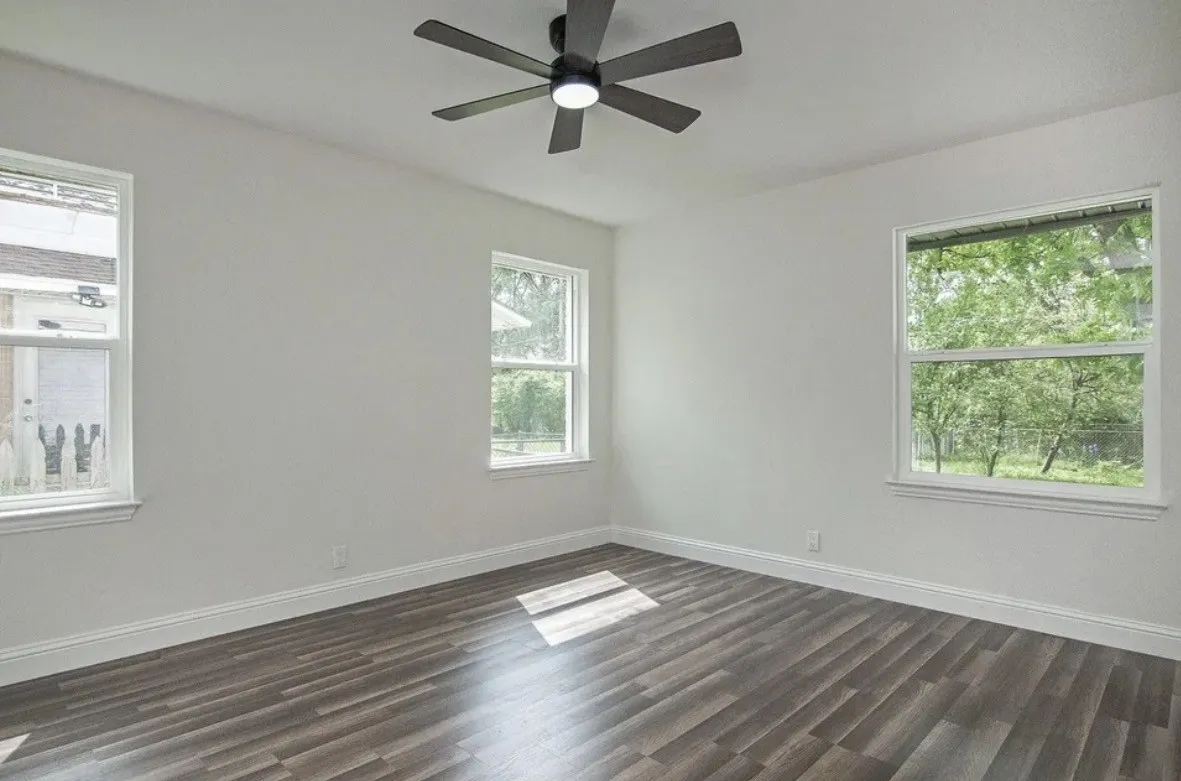 Spacious room featuring wood-finish flooring, white baseboards, and bright white walls