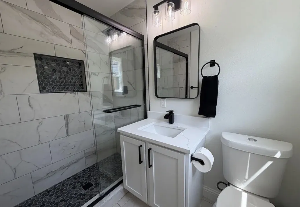 Modern bathroom featuring a glass-enclosed shower with large format tile walls and a pebble-tiled floor