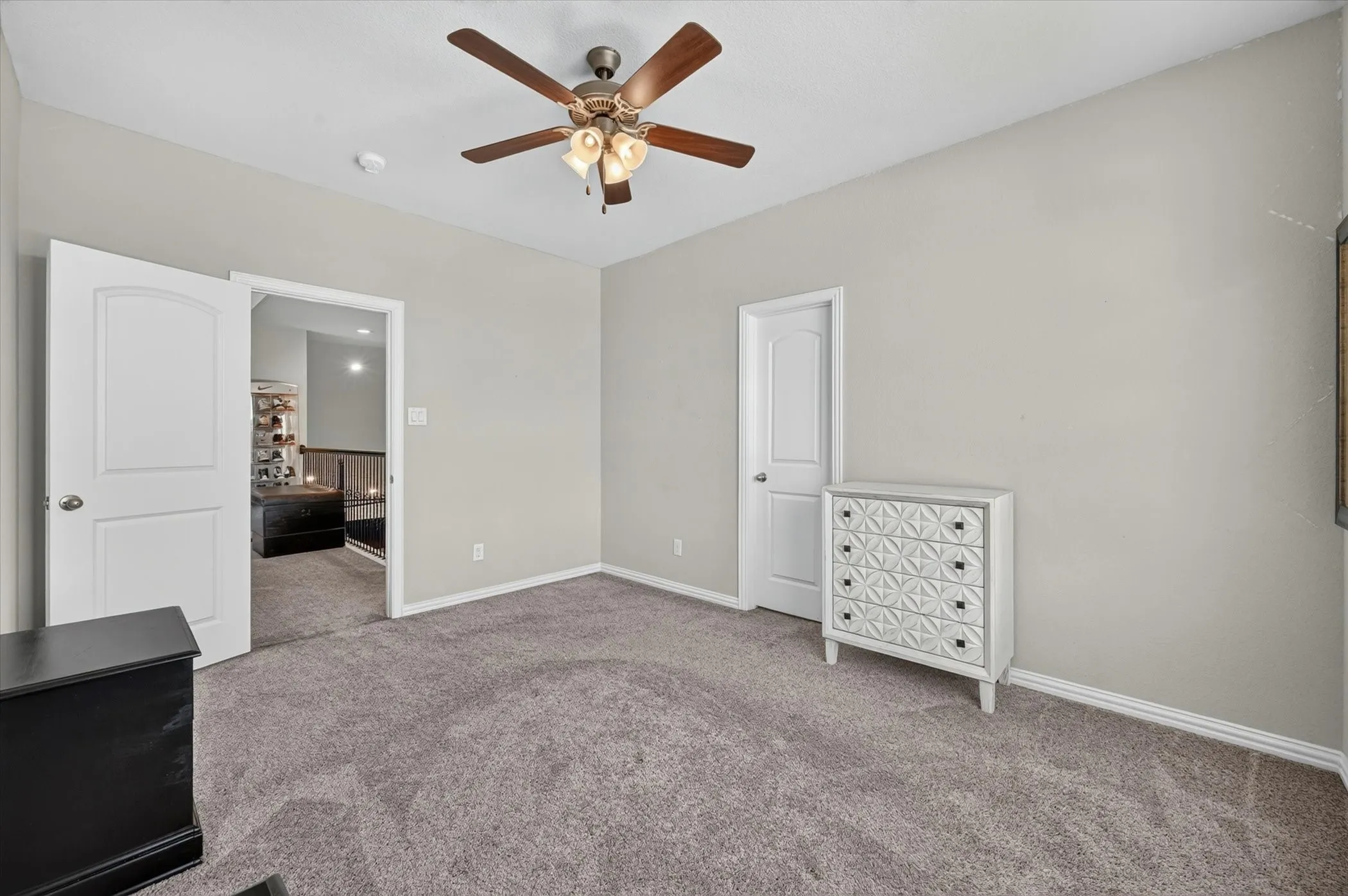 Room featuring neutral wall tones, gray carpeting, a ceiling fan with light fixture, white trim, and white paneled doors