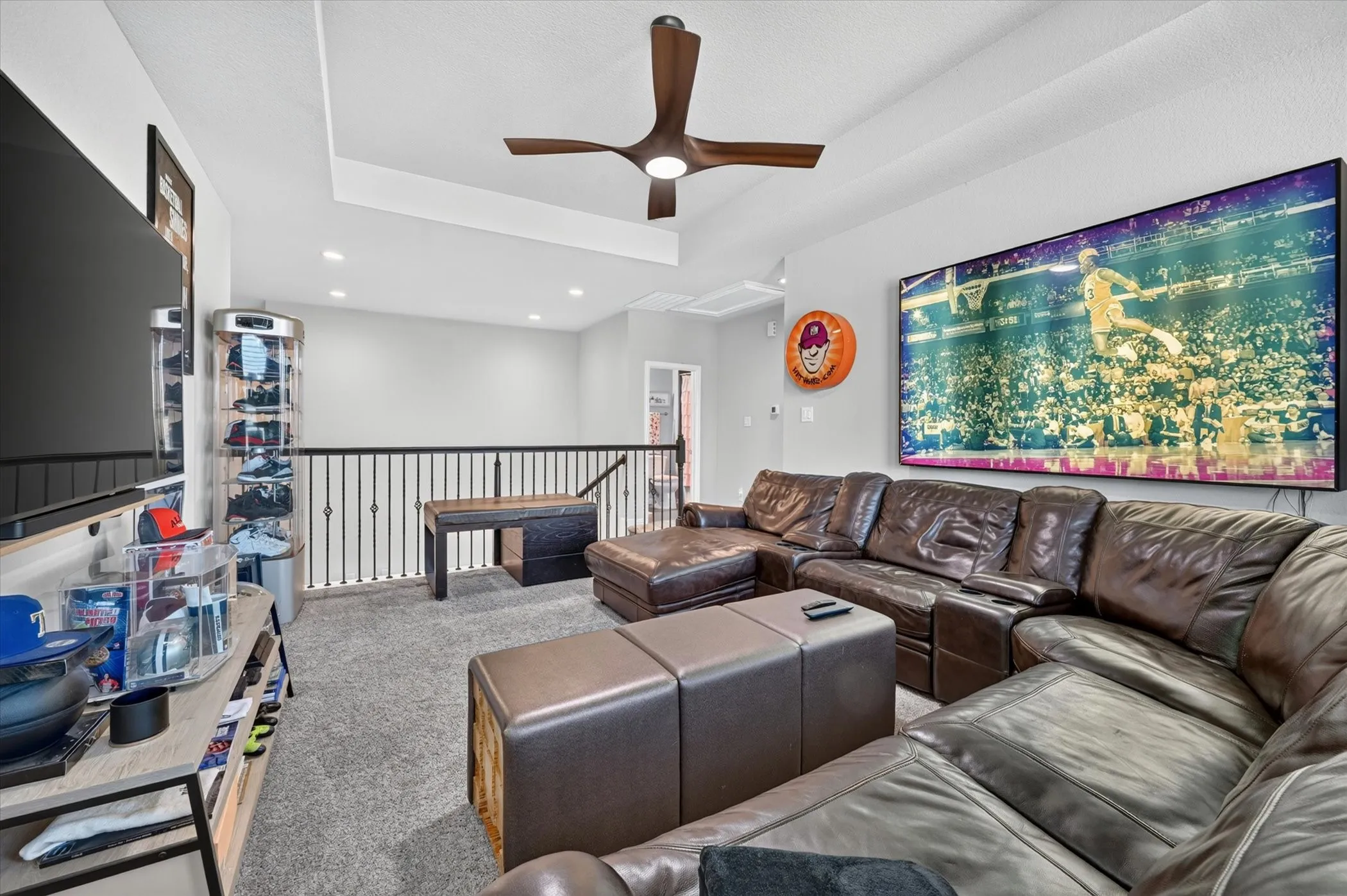 Open concept loft space featuring a tray ceiling with a modern ceiling fan, recessed lighting, and grey carpet flooring