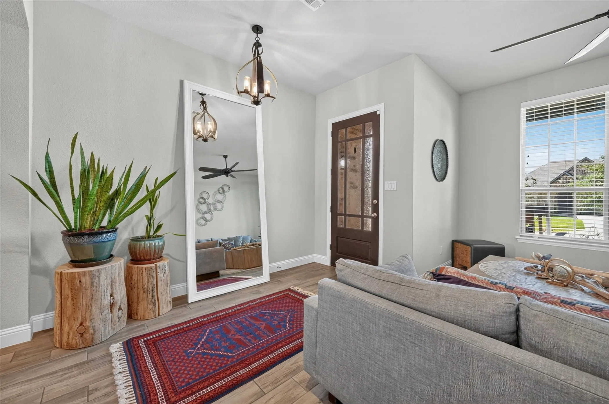 Entryway featuring wood-finish flooring, a dark wood-finish door with frosted glass panels, and a prominent window with blinds