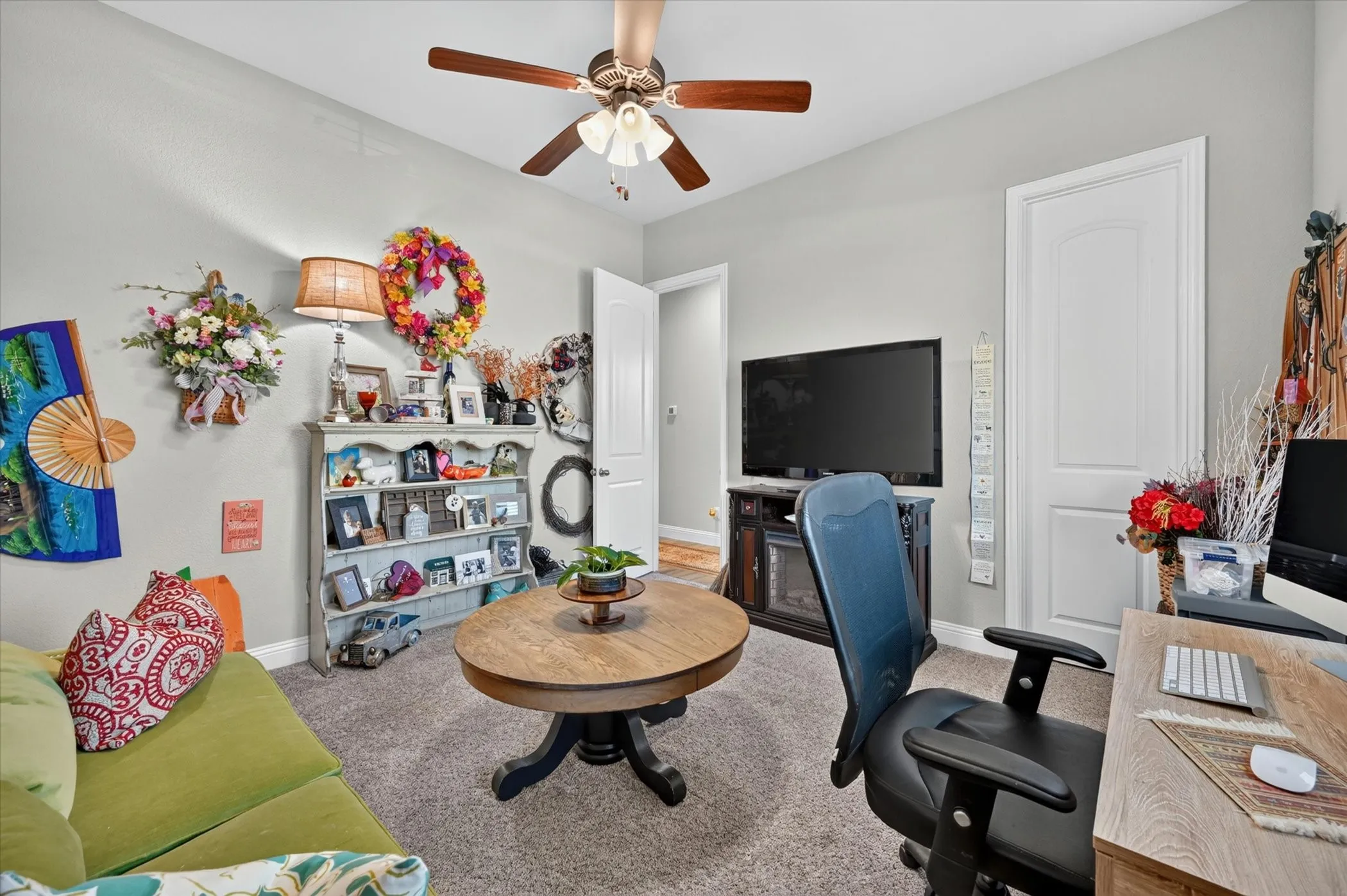 Interior room featuring light gray walls, textured carpet flooring, and a ceiling fan with integrated lighting
