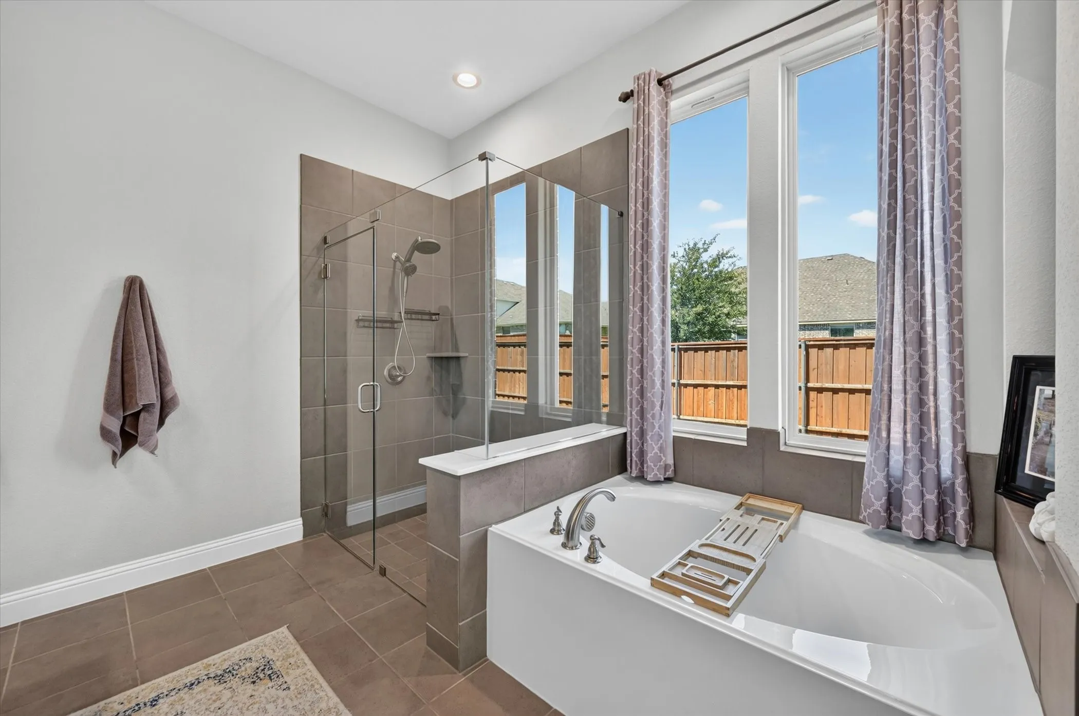 Soaking tub with chrome fixtures, framed by tall windows
