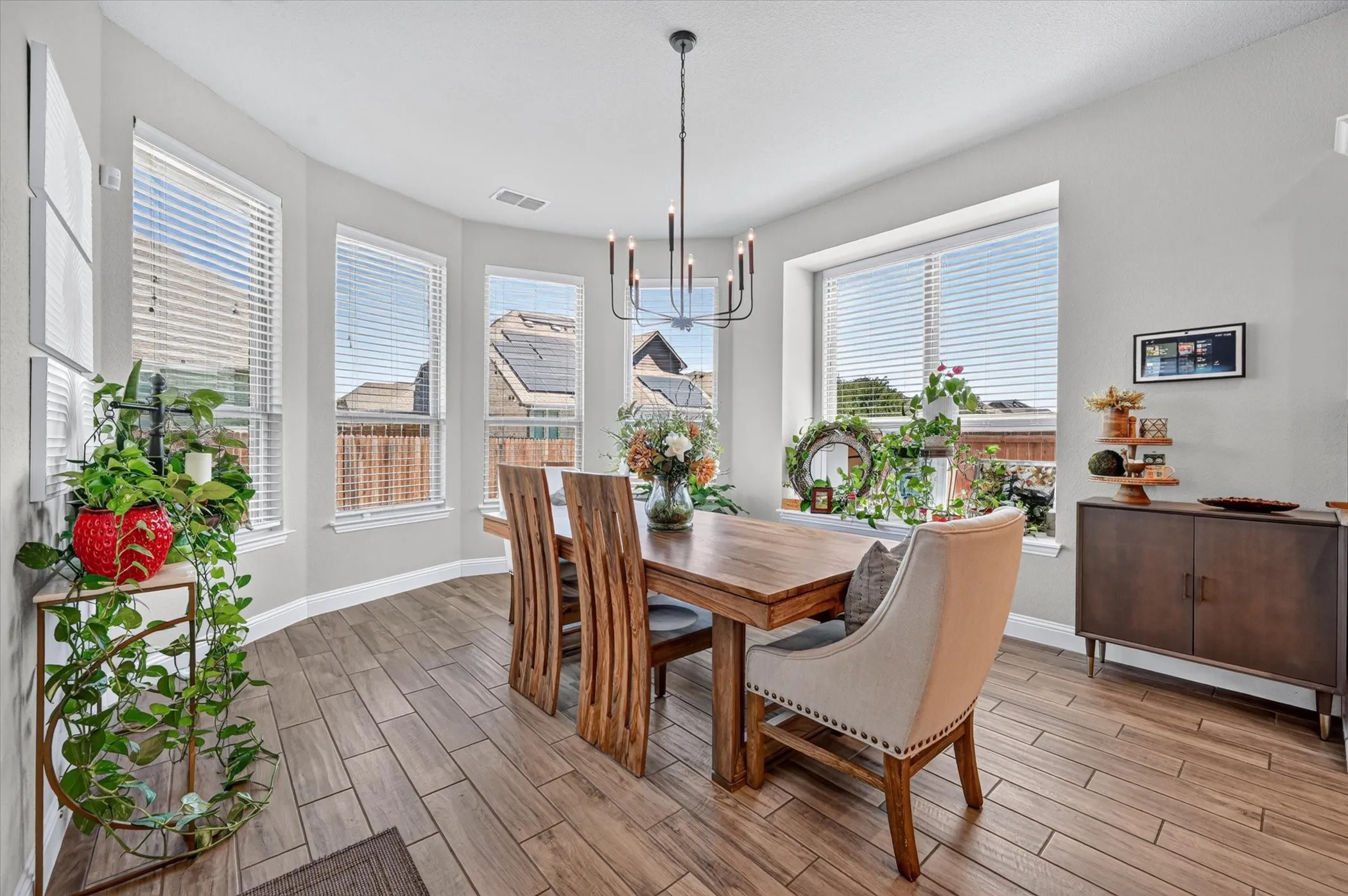 Dining space featuring wood-finish flooring, a contemporary chandelier, and multiple windows with blinds