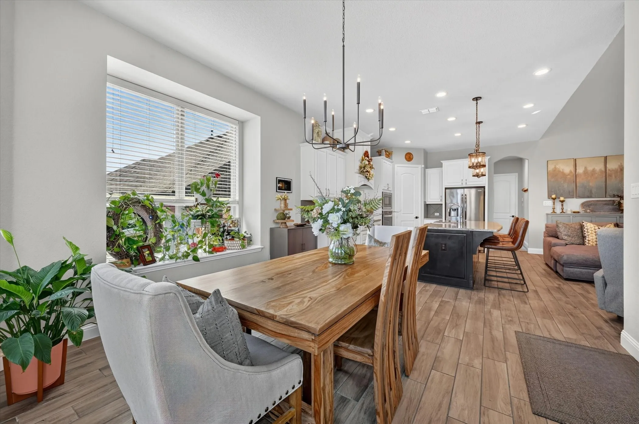 Dining area featuring a large window, wood-finish flooring, and an overhead chandelier