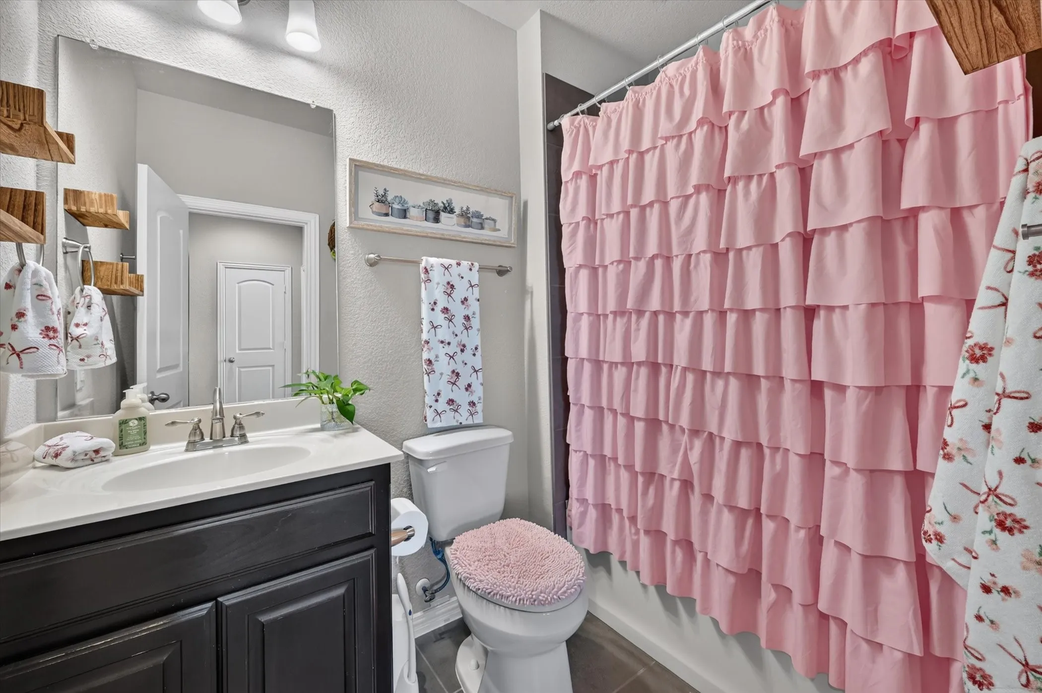 Bathroom featuring a single vanity with a dark wood-finish cabinet, integrated sink, and stainless steel faucet