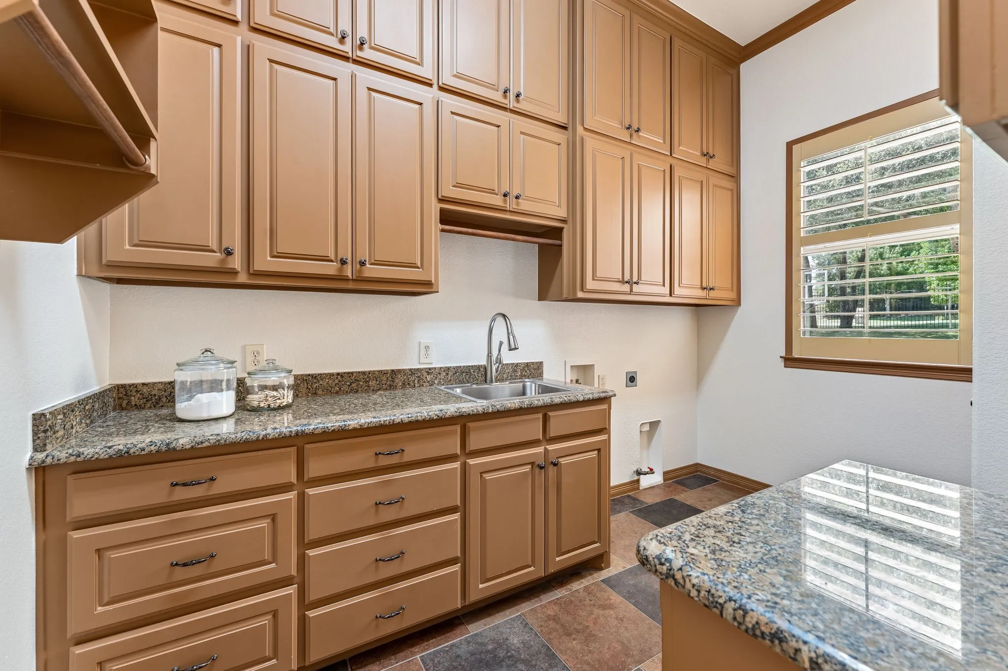 This light & bright laundry room offers a sink, abundance of storage, room for a fridge, hanging racks and closet.