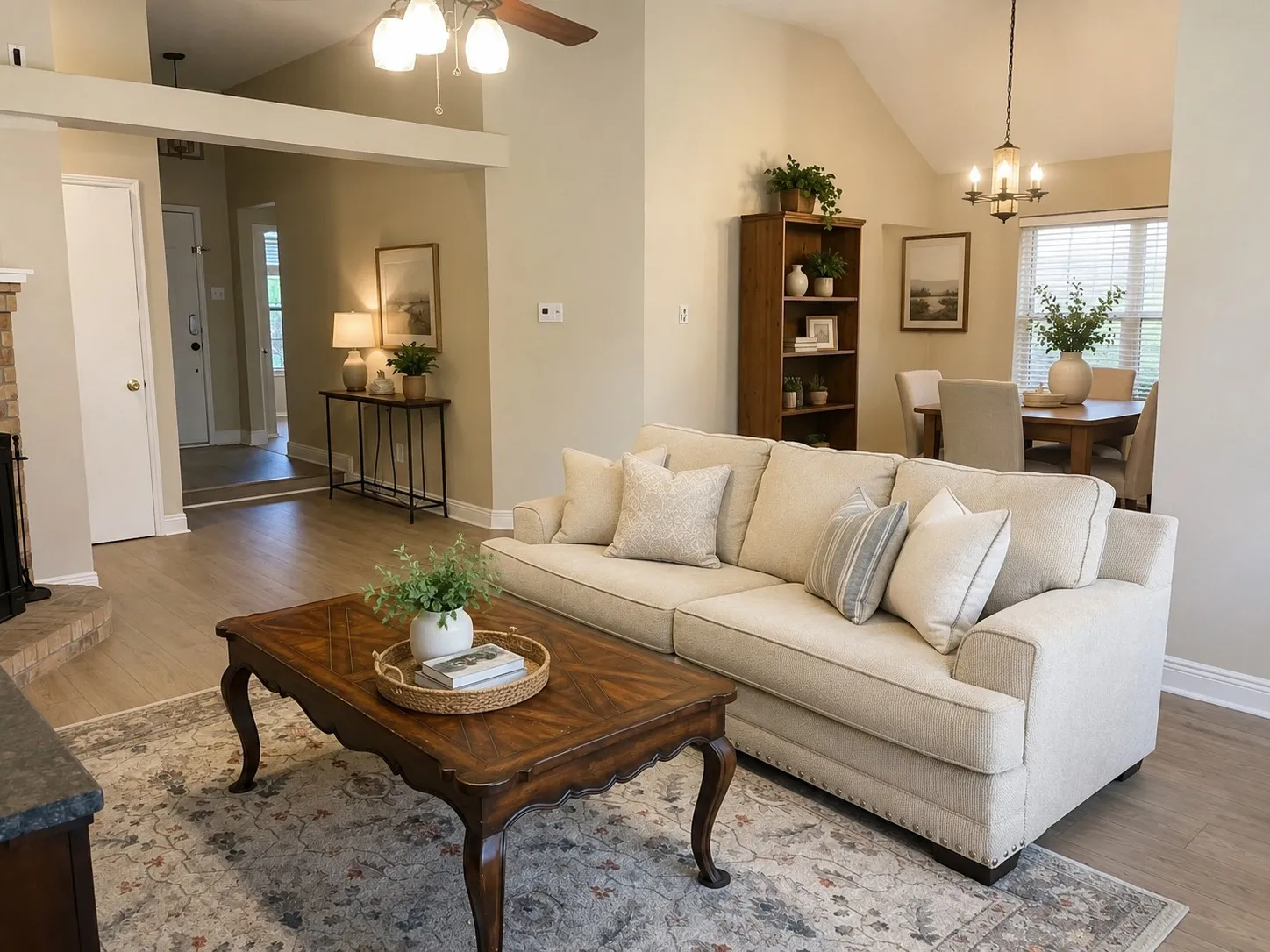 Living room with virtually staged dining room behind featuring vaulted ceilings and light wood-finish flooring define this inviting living space