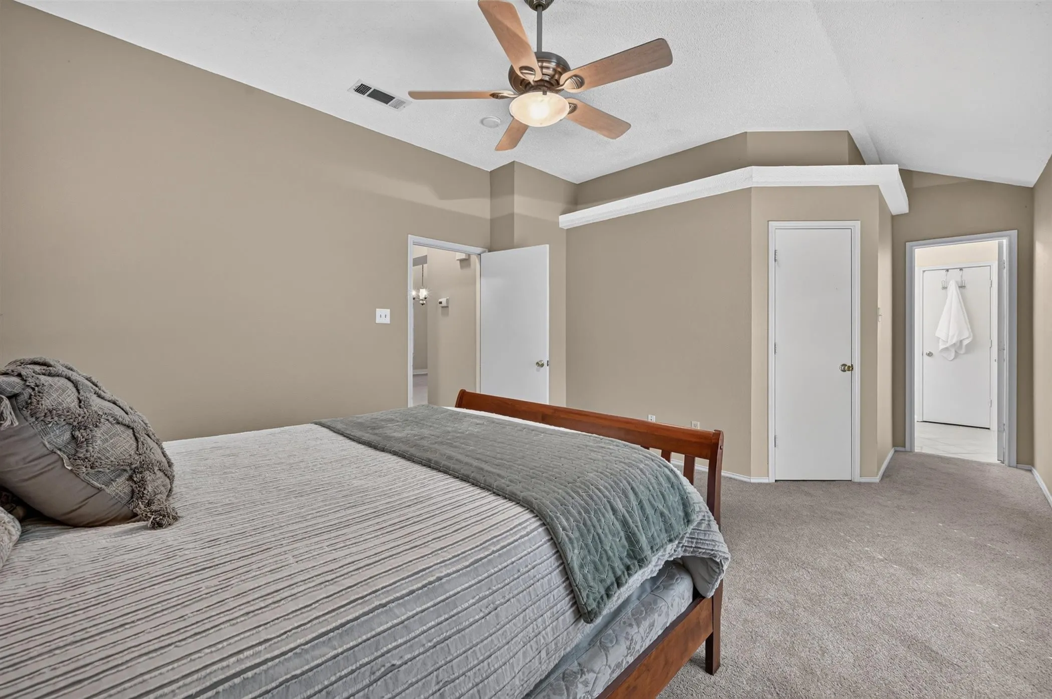 Carpeted room featuring a vaulted ceiling with a ceiling fan, neutral wall paint, and white trim