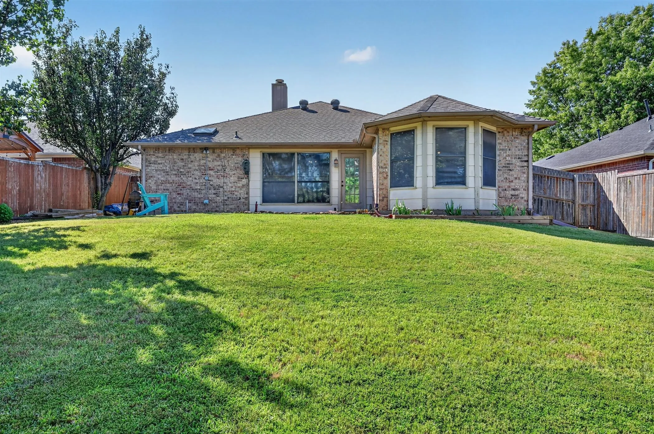 Spacious green lawn surrounding the rear exterior, featuring brick siding and a bay window