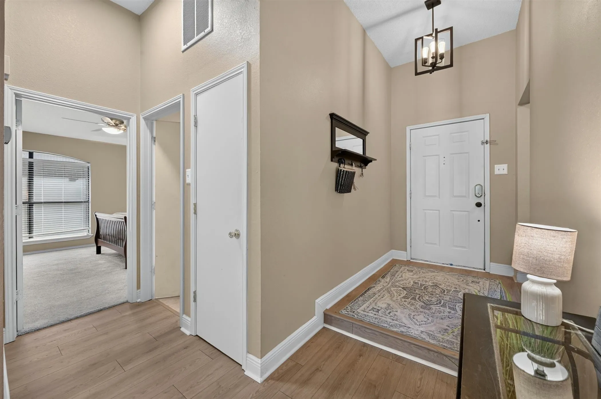 Entryway featuring wood-finish flooring, a vaulted ceiling, and a modern geometric pendant light fixture
