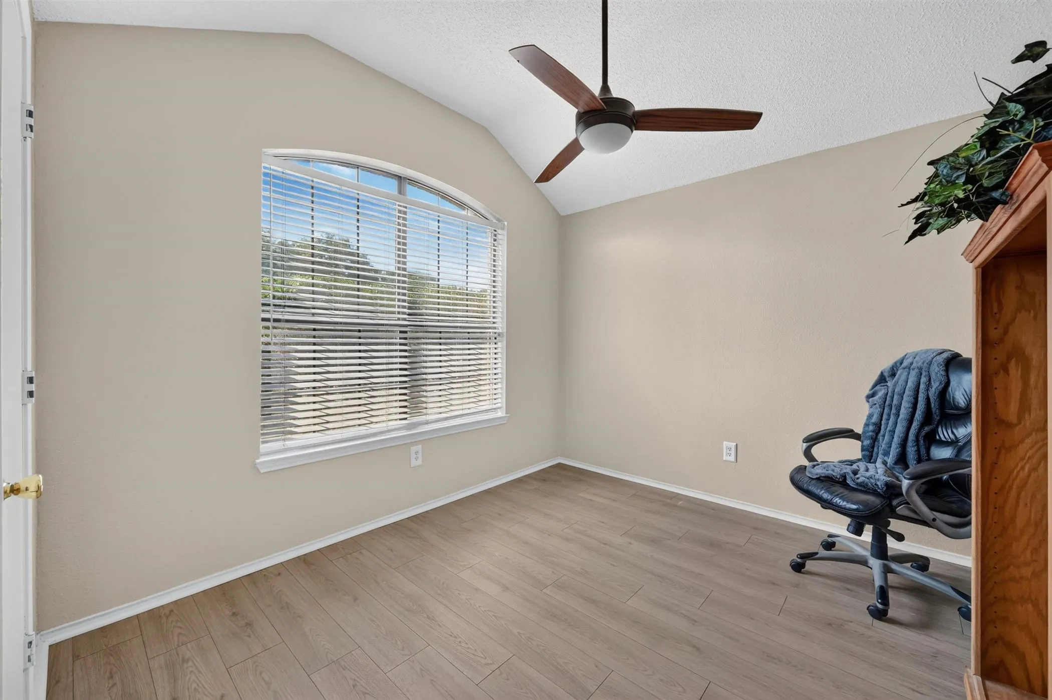 Room with vaulted ceiling, wood-finish flooring, and a large arched window. Front bedroom would also make a lovely office