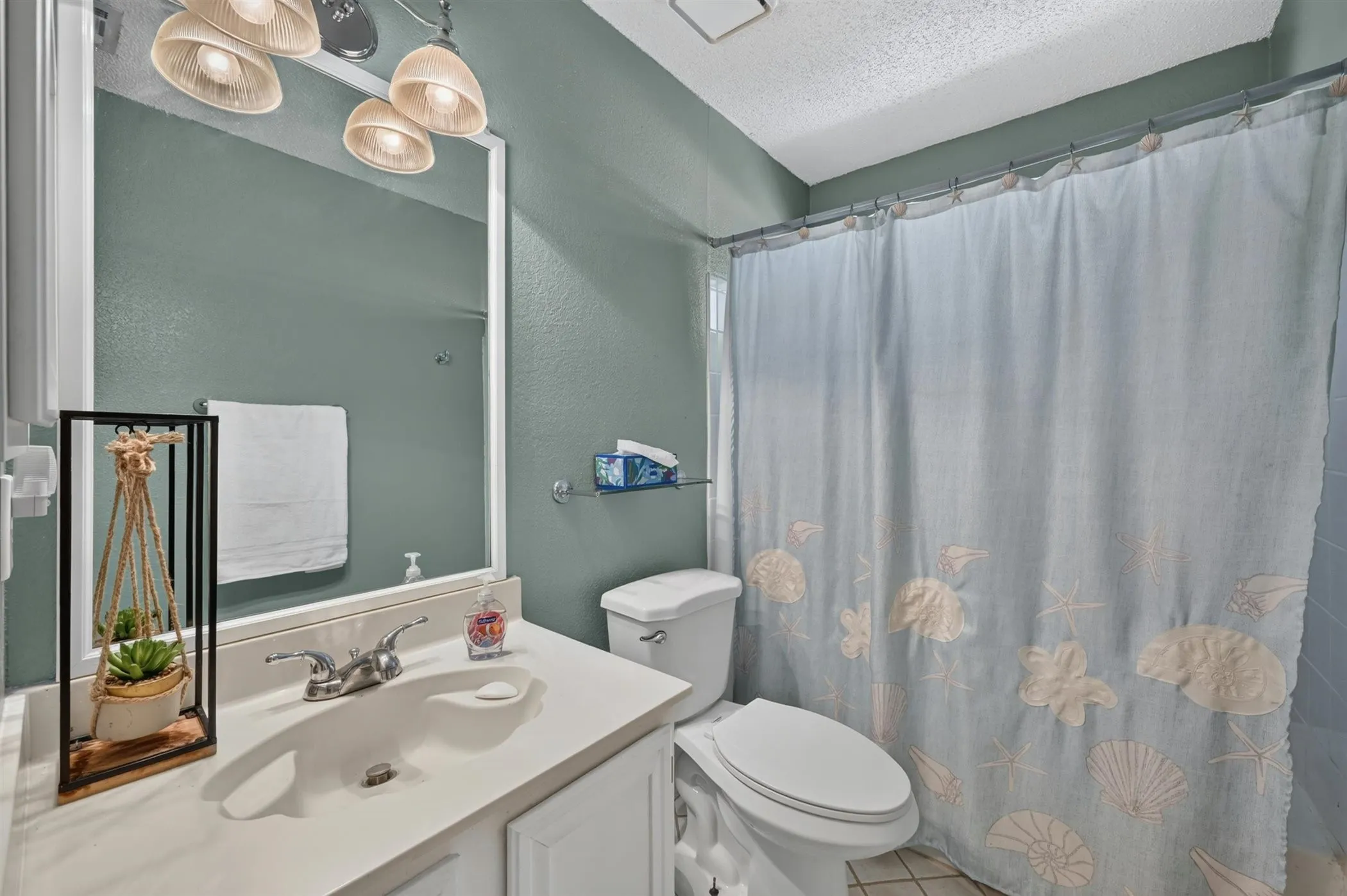 Bathroom vanity with integrated sink, white cabinetry, and wall-mounted mirror