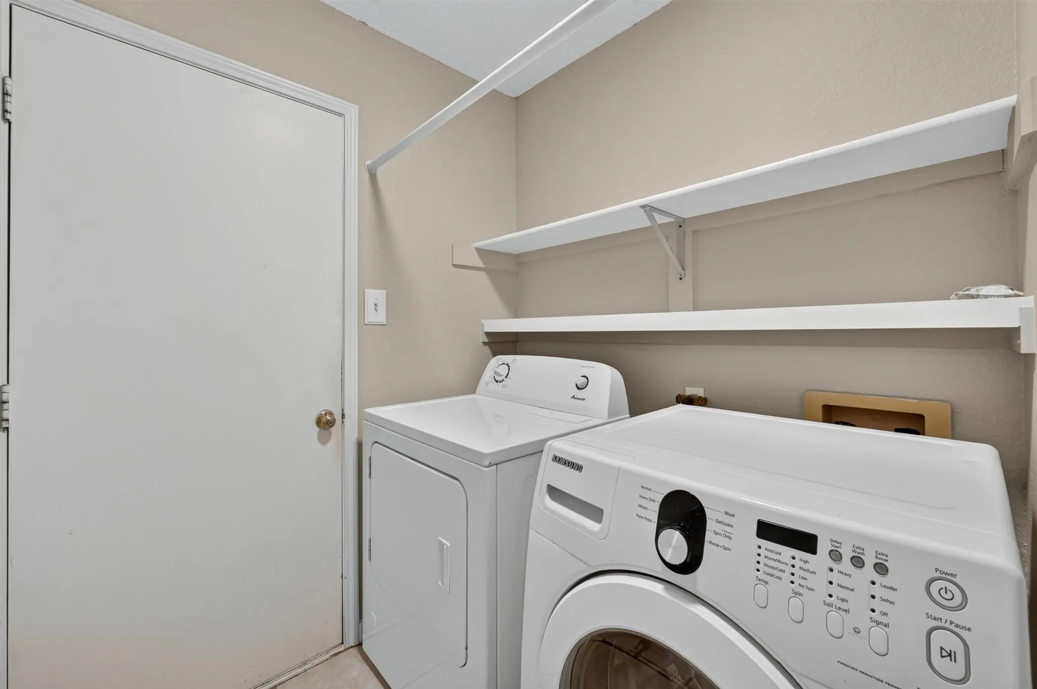 Dedicated utility area featuring a solid door, two white shelving units, and neutral wall tones